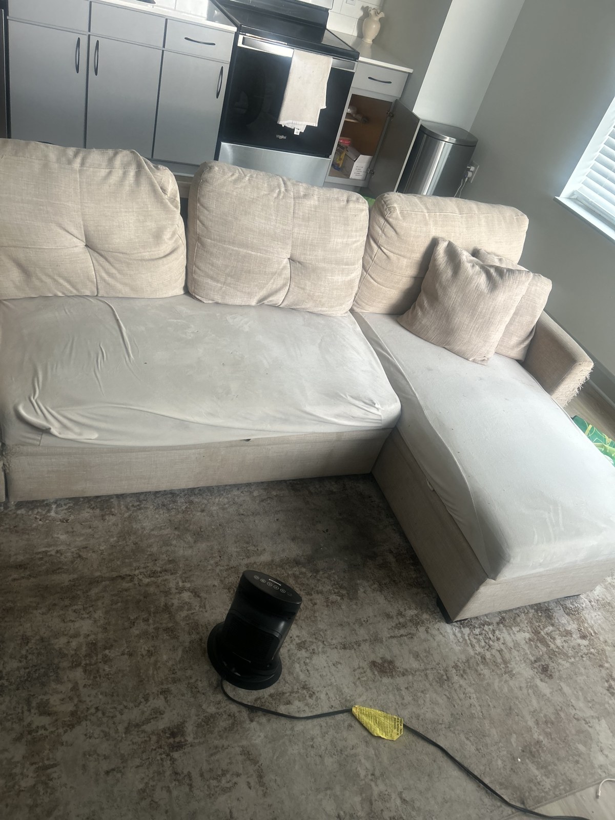 Beige sectional couch sitting in a customer's living room before removal
